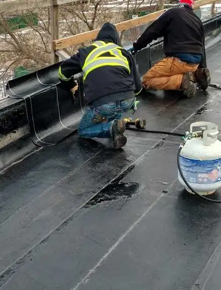 Modified membrane base sheet being torch welded to a perimeter wall